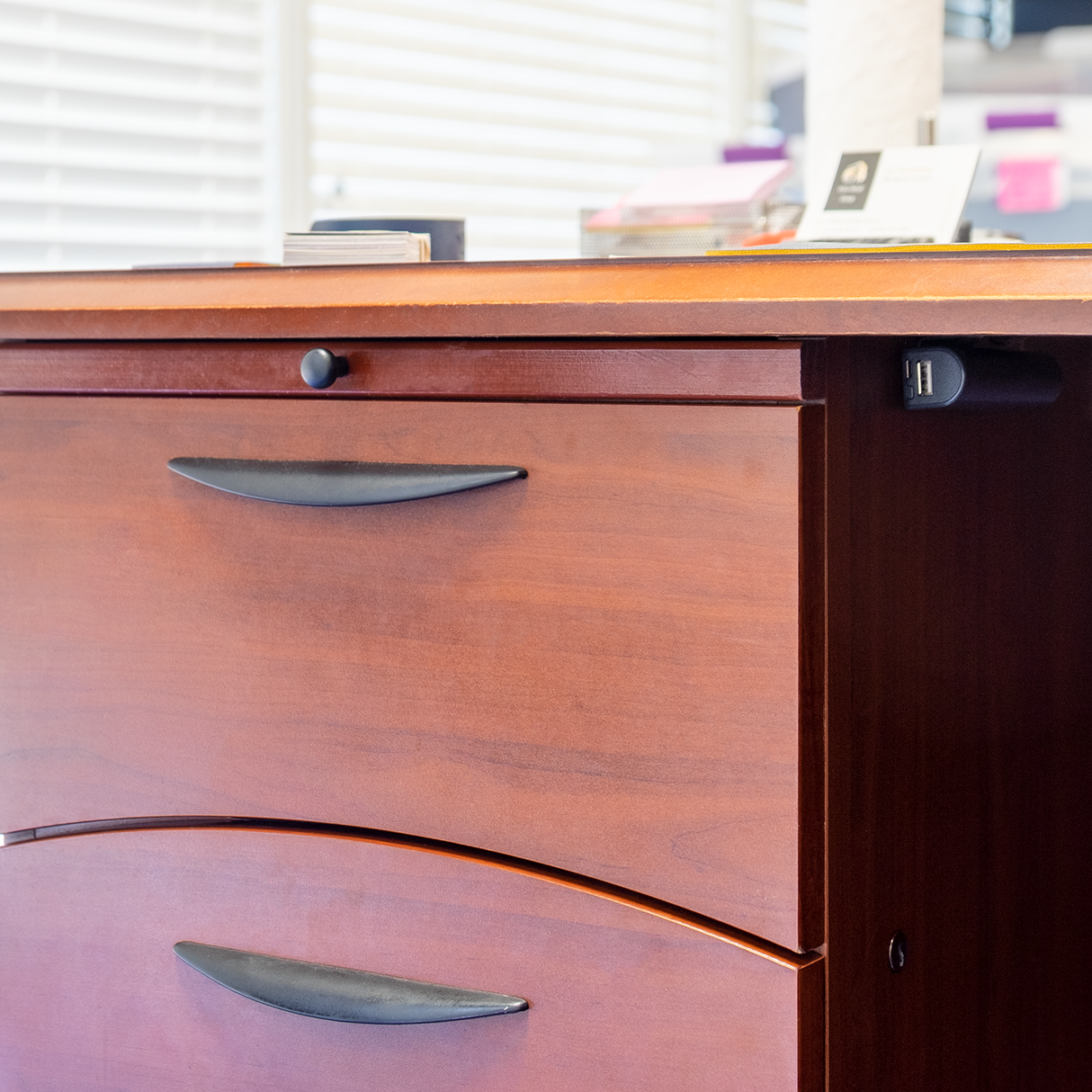 A black Rechargeable Voice Recorder & Power Bank actively charging a smartphone discreetly mounted underneath the desktop