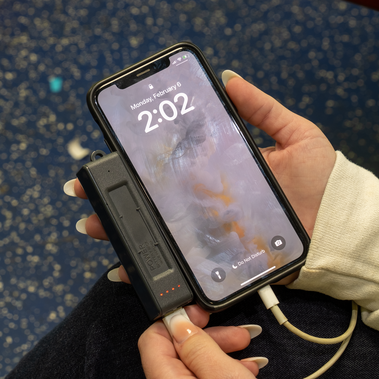 A black Rechargeable Voice Recorder & Power Bank actively charging a smartphone