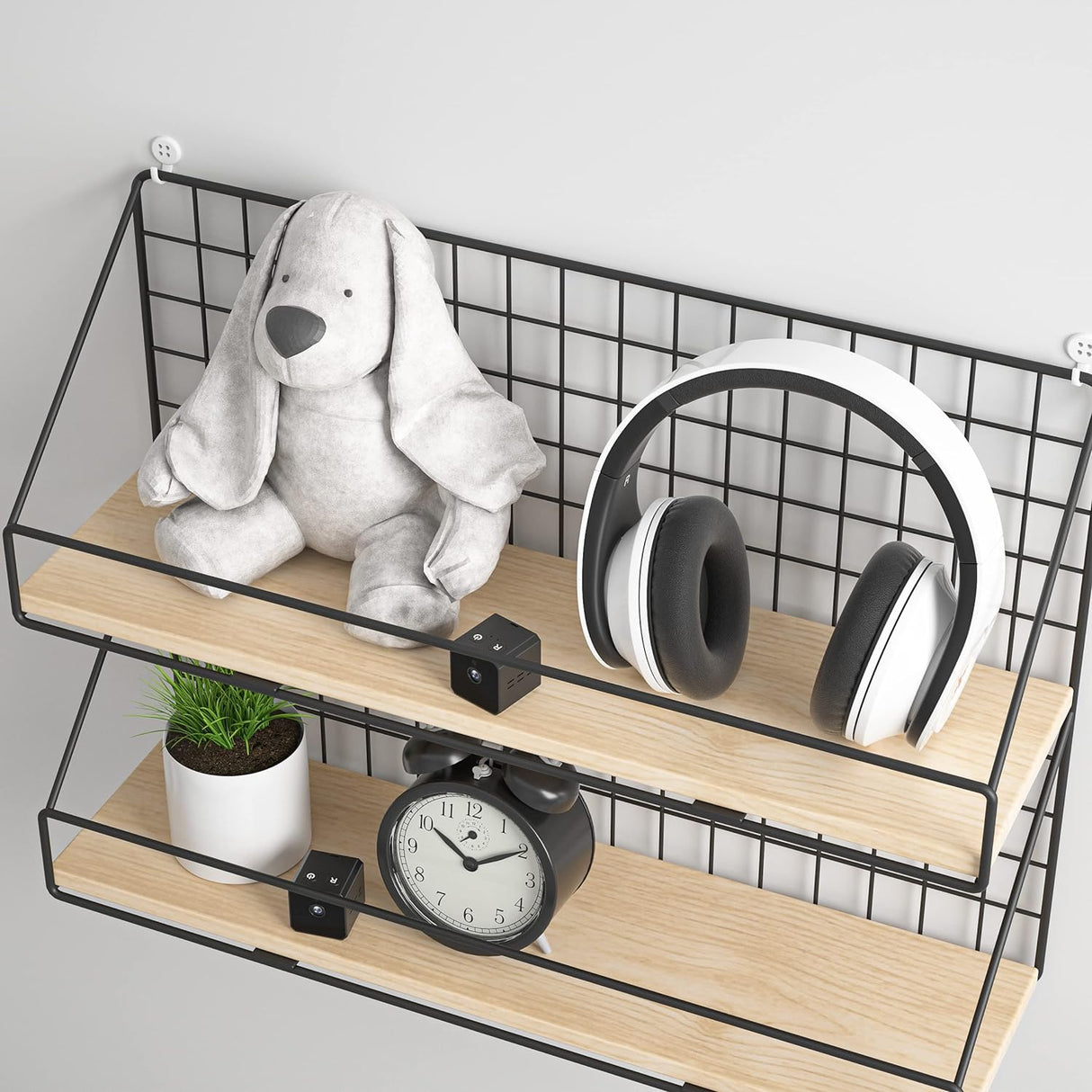 Two black SpyWfi mini travel Cube Camera hidden among decorative items on a wooden wire shelf