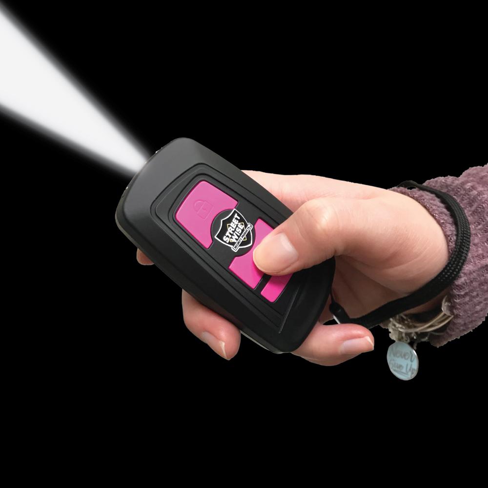 Black Fake Key Fob Mini Stun Gun Panic Alarm with pink buttons and wrist strap in hand