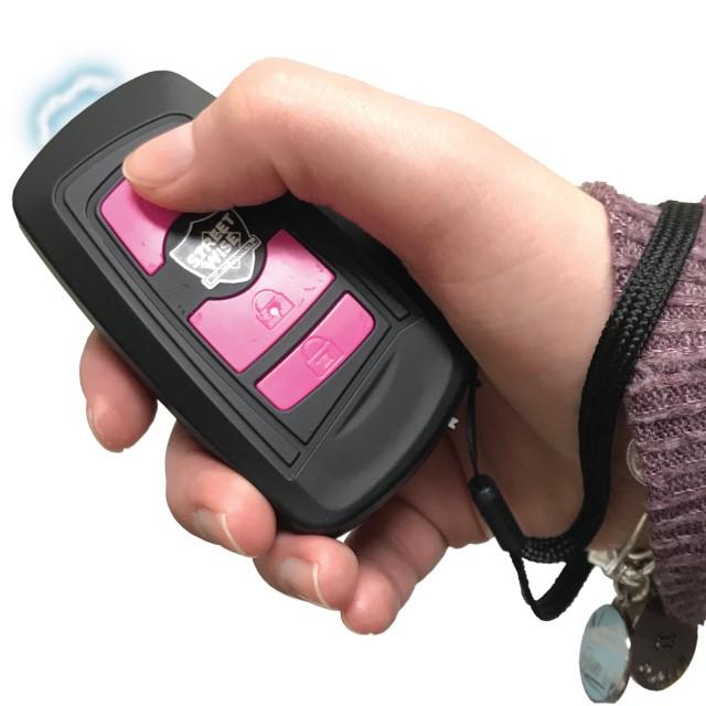 Black Fake Key Fob Mini Stun Gun Panic Alarm with pink buttons and wrist strap in hand
