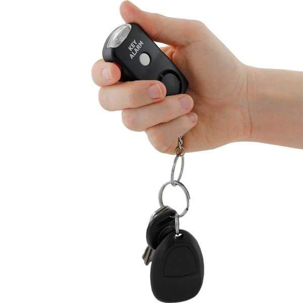 A hand holding a Black 130dB Keychain Panic Alarm with LED Light and keys attached