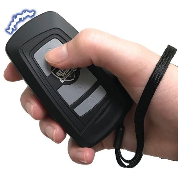 Black Fake Key Fob Mini Stun Gun Panic Alarm with silver buttons and wrist strap in hand
