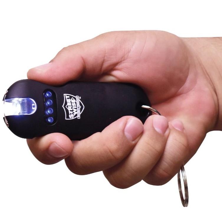 Black stun gun from Streetwise with flashlight on held by a hand in white background