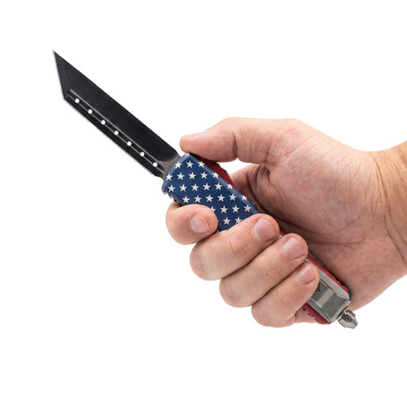Automatic OTF knife with an American flag held against a white background.
