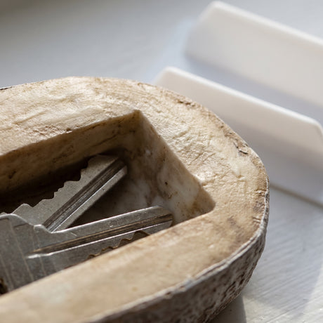 Close-up of a fake rock key holder with keys inside on a white surface
