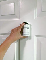 A Hand installing a white Guardian Angel Home Defender on a white door