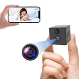 A  hand holding a SpyWfi Mini Travel Cube Hidden Night Vision Spy Camera 2K HD WiFi next to a smartphone displaying a real time recording