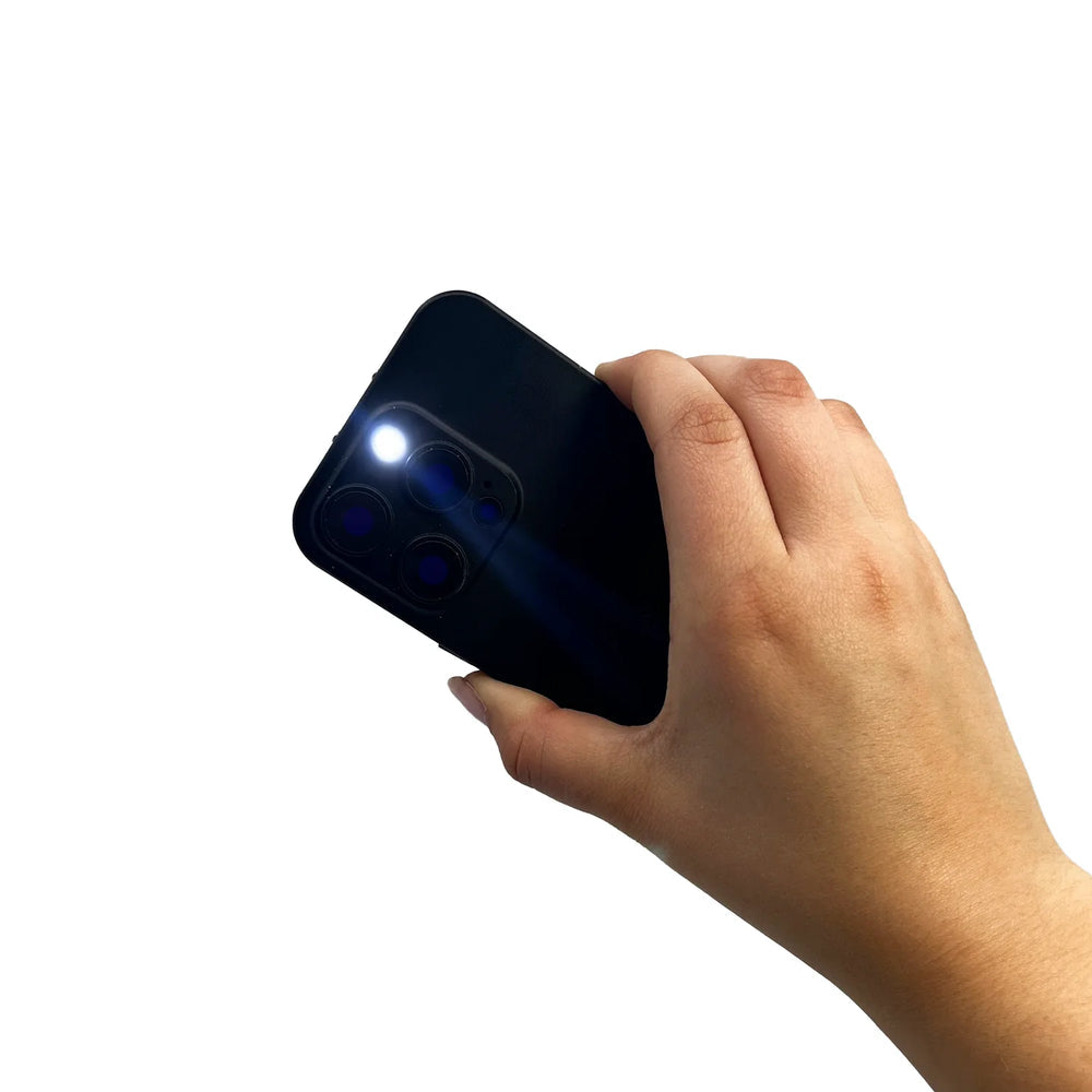 A hand holding a stun gun disguised as black smartphone with flashlight on