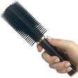 A hand holding a black hair fryer brush that is actually a disguised rechargeable stun gun.