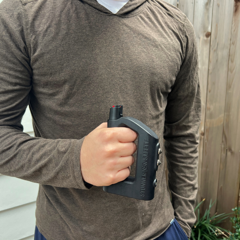 a man holding a The Stunner 3-in-1 Rechargeable LED Stun Gun Pepper Spray Jogger Combo on his hand