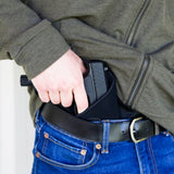 a hand putting a gun inside a Uncle Mike's Size 5 IWB Right Hand Holster attached to his waist