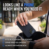 A person holding a black smartphone case over an open bag, with promotional text reading 'LOOKS LIKE A PHONE. READY WHEN YOU NEED IT.