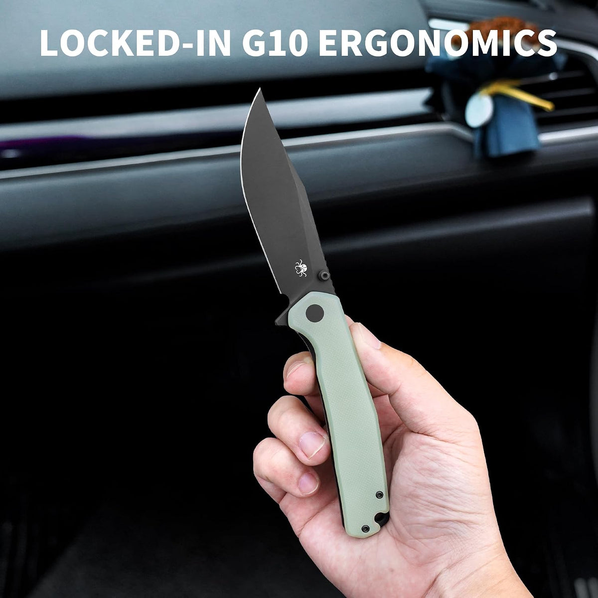 A hand holding a folding pocket knife with a matte black blade and an olive green handle, set against a dark car interior background with the text 'LOCKED-IN G10 ERGONOMICS' at the top.
