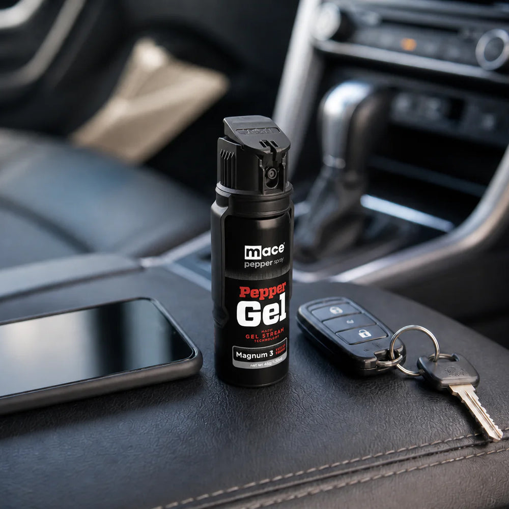 Mace pepper gel placed on a car center console beside a smartphone and vehicle keys