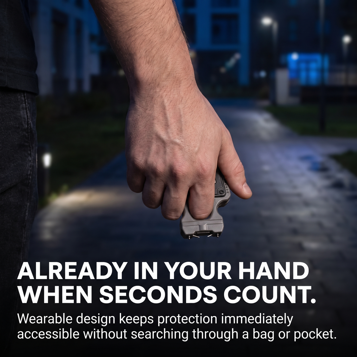 A close-up of a person's hand holding a small rectangular wearable safety device on a blurred nighttime outdoor path. Large text at the bottom reads, 'ALREADY IN YOUR HAND WHEN SECONDS COUNT.
