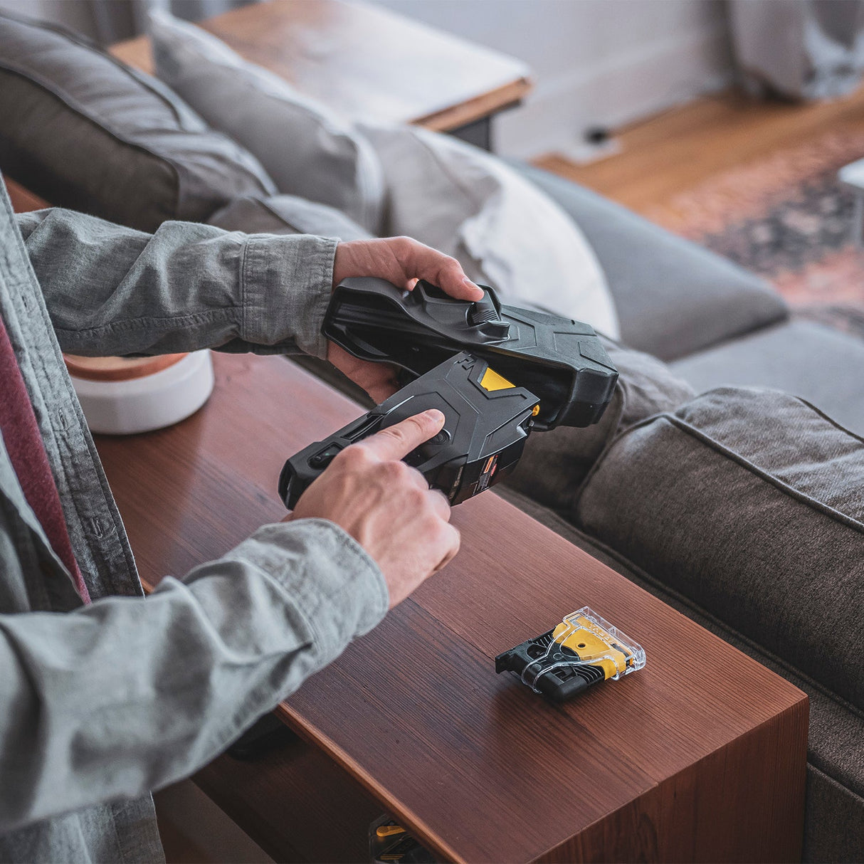 Person loading TASER X2 cartridge and holster setup inside a home setting