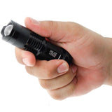 A hand holding a black 3.5" Police Force Tactical Mini Q5 LED Zoom Flashlight 220 Lm