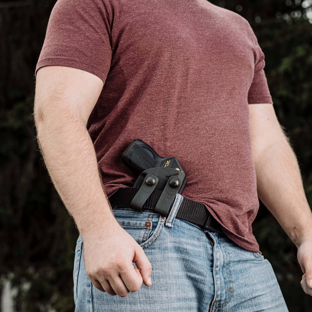 A man concealing a black Taser in a black Blade-Tech IWB Kydex holster worn on his belt