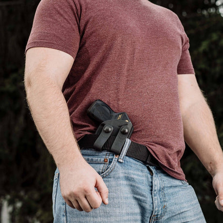 A man concealing a black Taser in a black Blade-Tech IWB Kydex holster worn on his belt