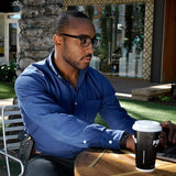 Man working on a laptop outdoors while carrying the black TASER Pulse and Kydex holster worn on his belt loop