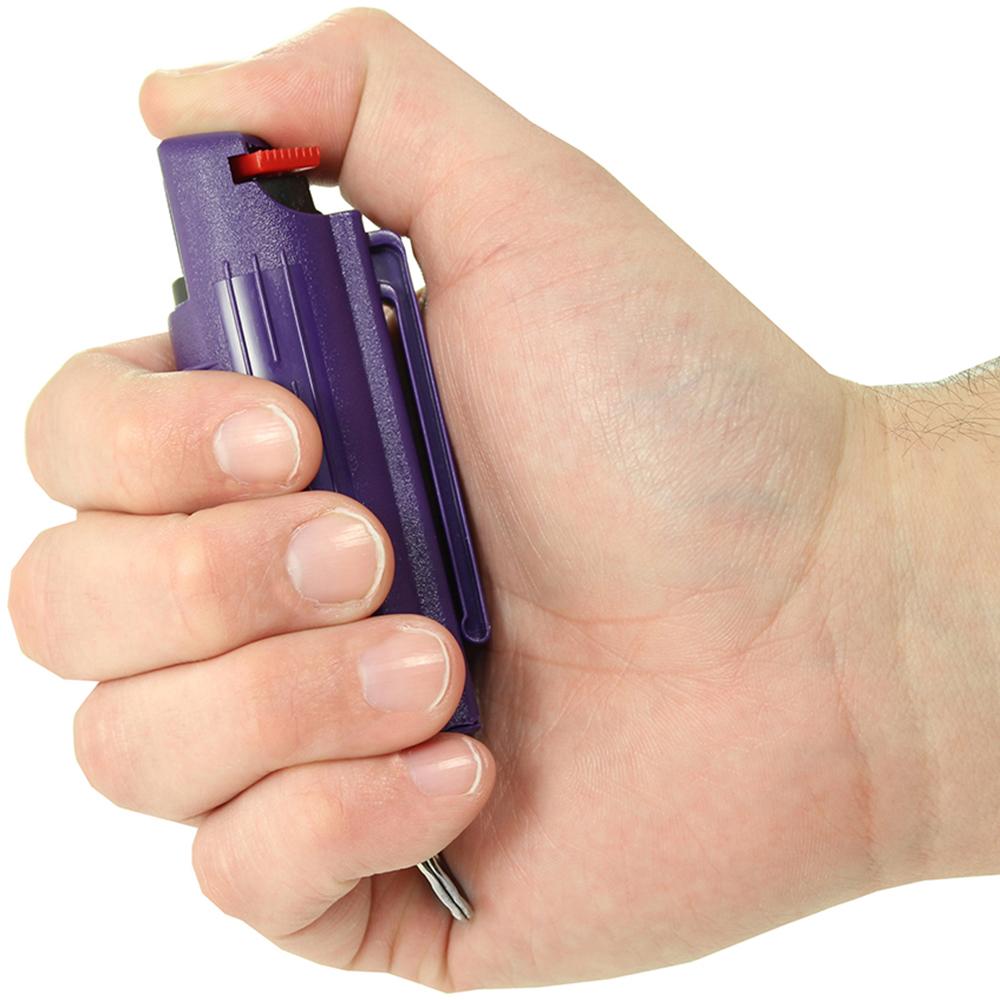 A hand holding a purple Eliminator Blue Heat Keychain Pepper Spray w/ Marking Dye