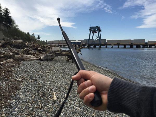 A hand holding a 16" Rothco Expandable Carbon Steel Spring Coil Baton outdoor