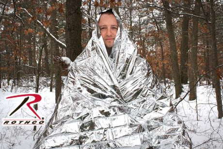 Person wrapped in Rothco Polarshield 1-Person Polyester Thermal Survival Blanket sitting in a snowy forest