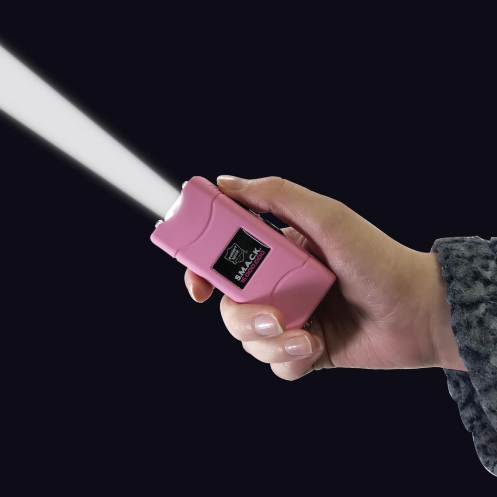 A hand holding a Streetwise S.M.A.C.K. Keychain Stun Gun 16M with flashlight on