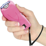 A hand holding a Pink Mini Rechargeable Stun Gun with wrist strap from Streetwise