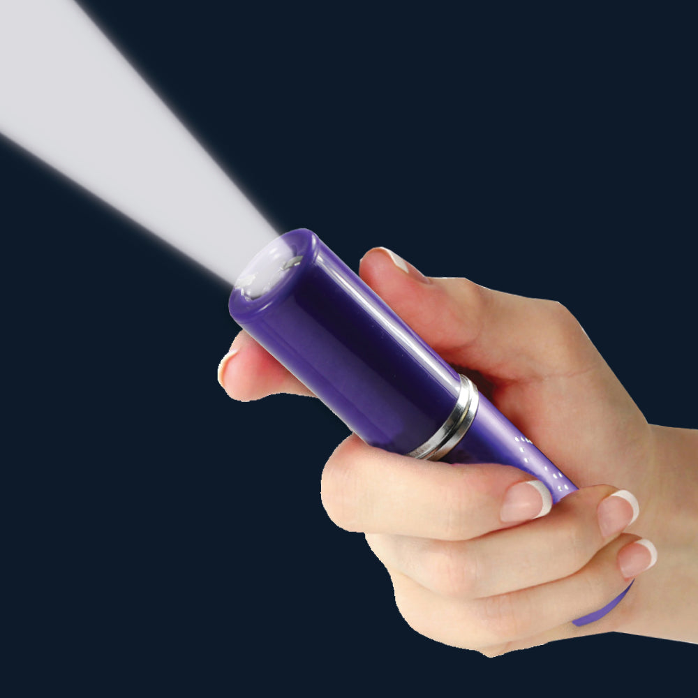 a hand holding a violet Streetwise™ Perfume Protector Disguised Rechargeable Stun Gun 17M with its flashlight on