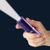 a hand holding a violet Streetwise™ Perfume Protector Disguised Rechargeable Stun Gun 17M with its flashlight on