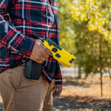 A person holding a TASER 7 CQ Home Defense Shooting Stun Gun in their hands, with the holster visible on their belt