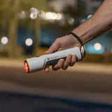a hand holding a TASER Strikelight 2 Rechargeable Stun Gun Flashlight with its red light on