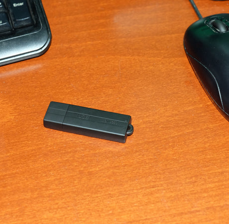 Black Voice Activated USB Drive Voice Recorder on a brown table